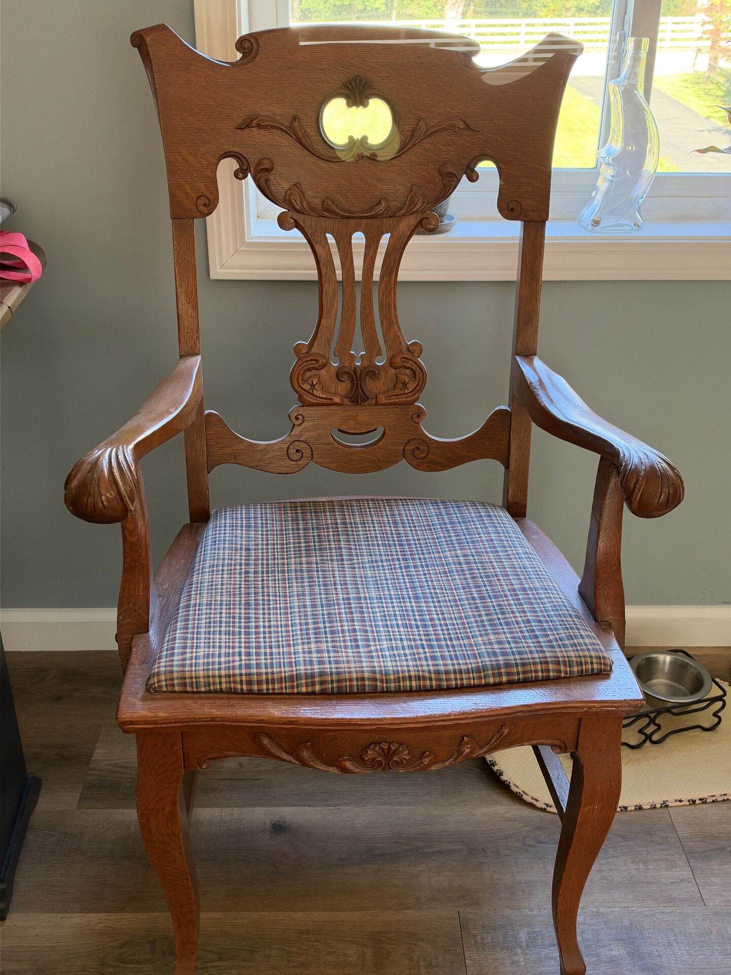 Ornamental wooden armchair with a carved backrest, scrolled arms and a plaid upholstered seat